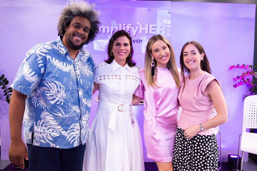 Four panelists posing together at an AmplifyHER event, including host Cristina Tamayo, Mercibel Gonzalez of Abarca Health, Sofía Stolberg of Piloto 151, and Devin Baptiste of Endeavor, smiling in front of event branding after a discussion on leadership and mentorship.