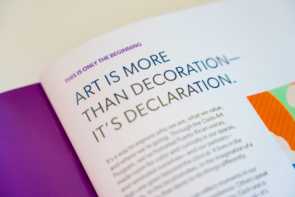 Open booklet by Abarca Health showing an interior page with the headline “ART IS MORE THAN DECORATION—IT’S DECLARATION.” Above it reads “This is only the beginning,” with a paragraph below explaining the role of art in expressing identity, values, and community, alongside colorful graphic elements on the page.